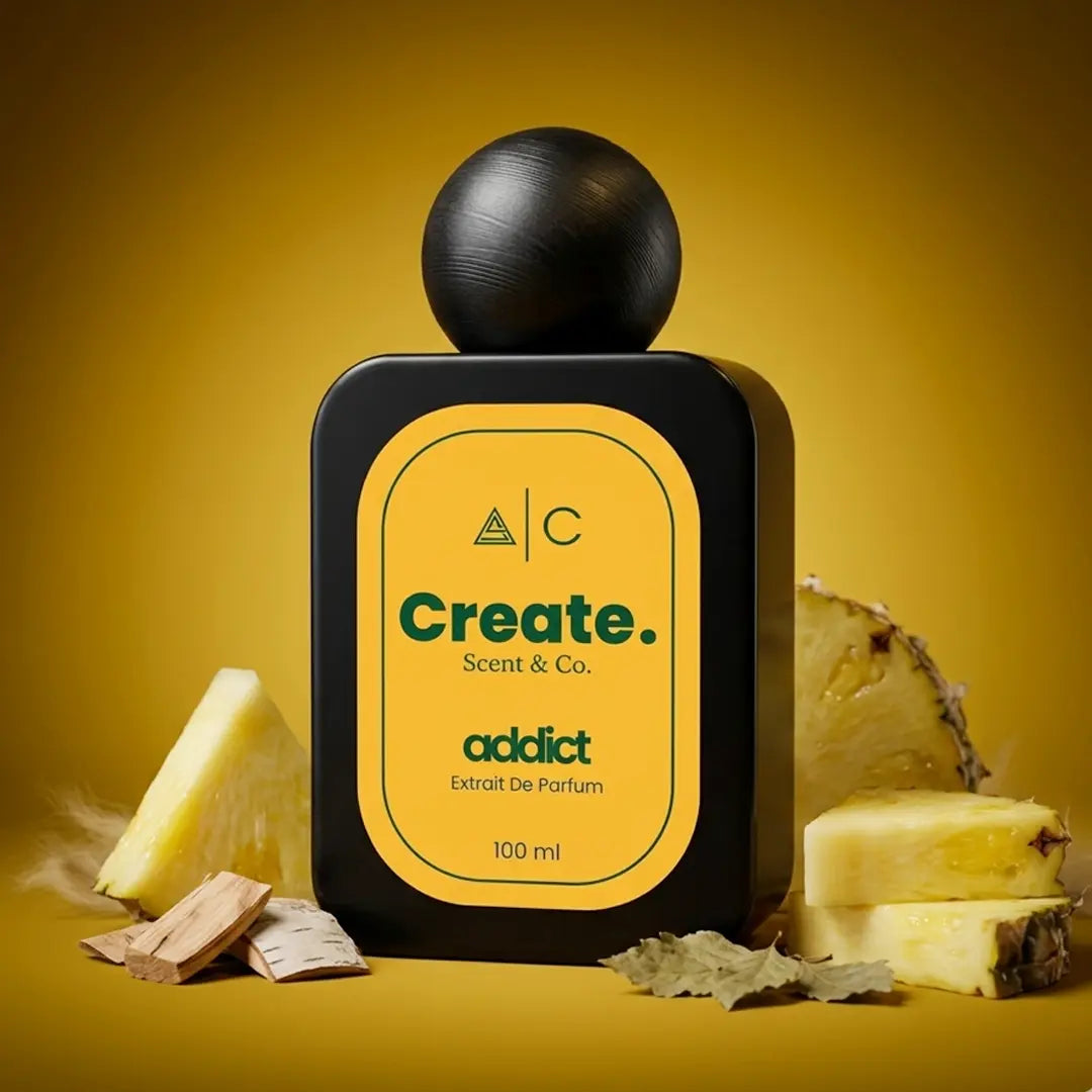 Create. Scent & Co. Addict Extrait De Parfum 100ml surrounded by fresh pineapple chunks, sandalwood and birch bark on a golden amber background